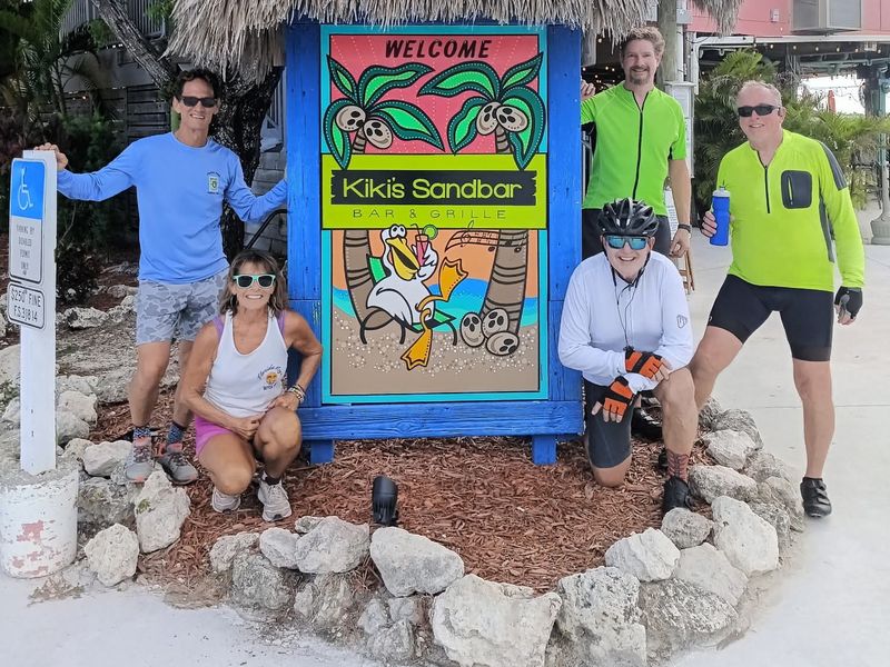 Riders at the Kiki's Sandbar sign during a ride stop